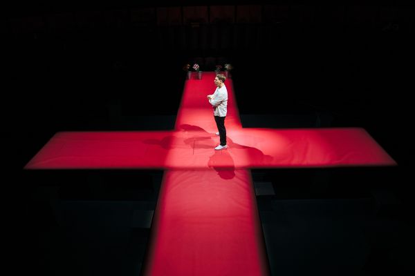 Michael (played by Thomas Coombes) stands in the centre of the stage which is in the shape of the Saint George's red cross