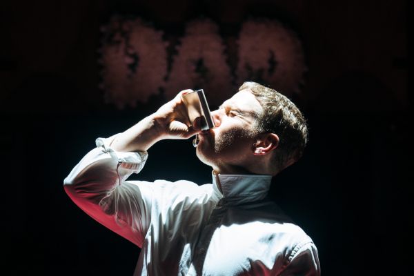 Michael (played by Thomas Coombes) drinks from a hip flask in front of a sign that says 'DAD'